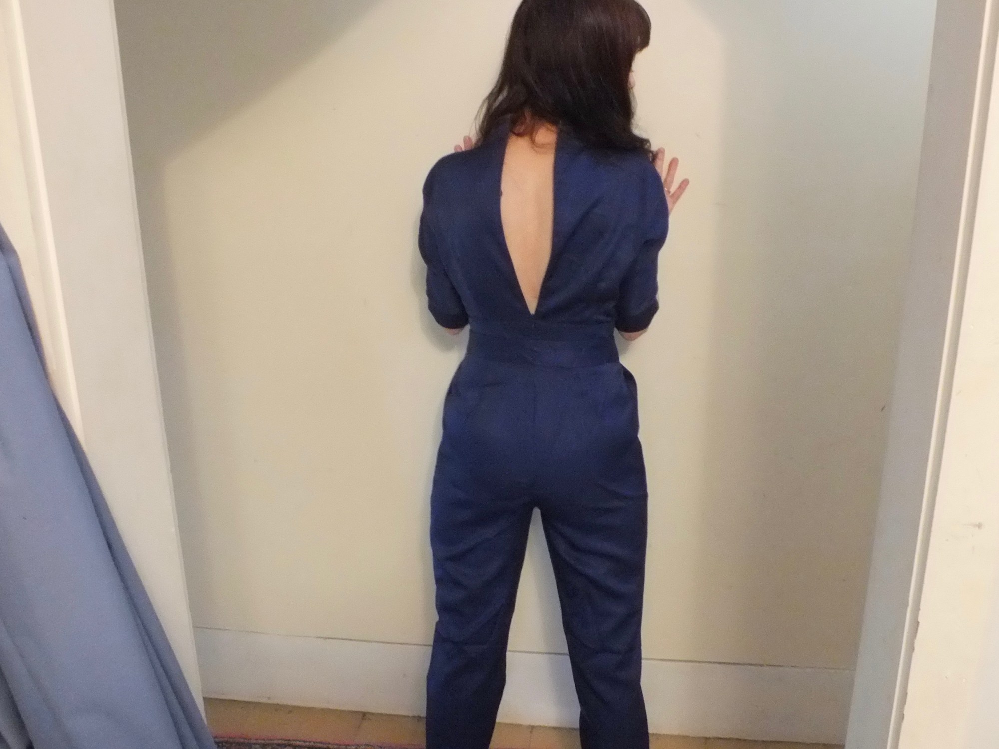 navy blue jumpsuit from an online Shanghai-based company called Rotital a woman with her back to the camera with a gaping zipper on the jumpsuit.